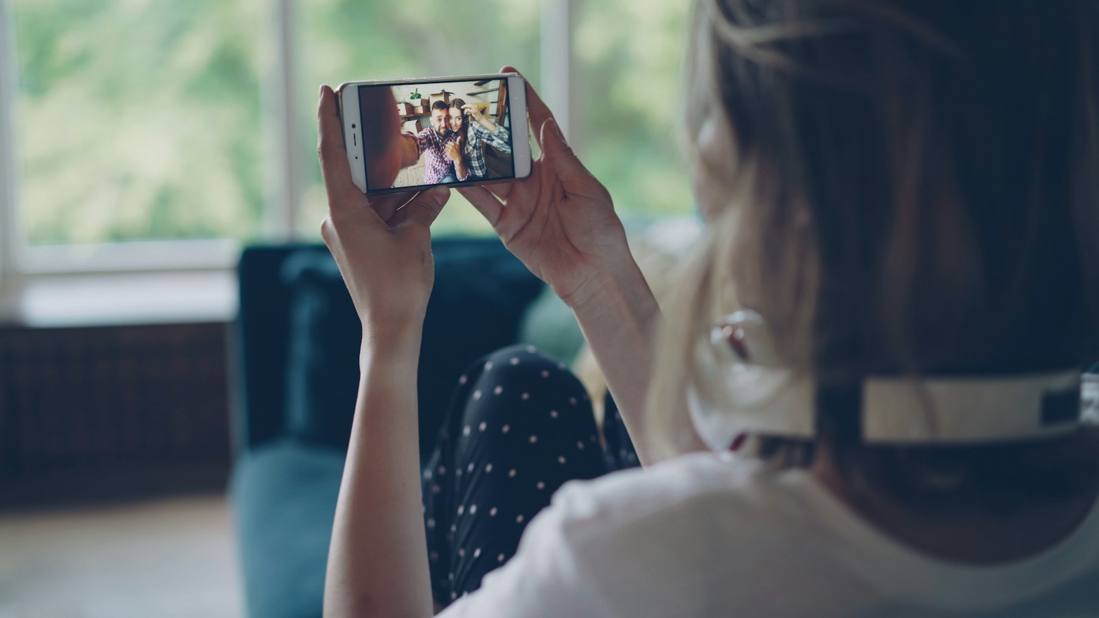 A viewer holding a smartphone and watching a video at home.